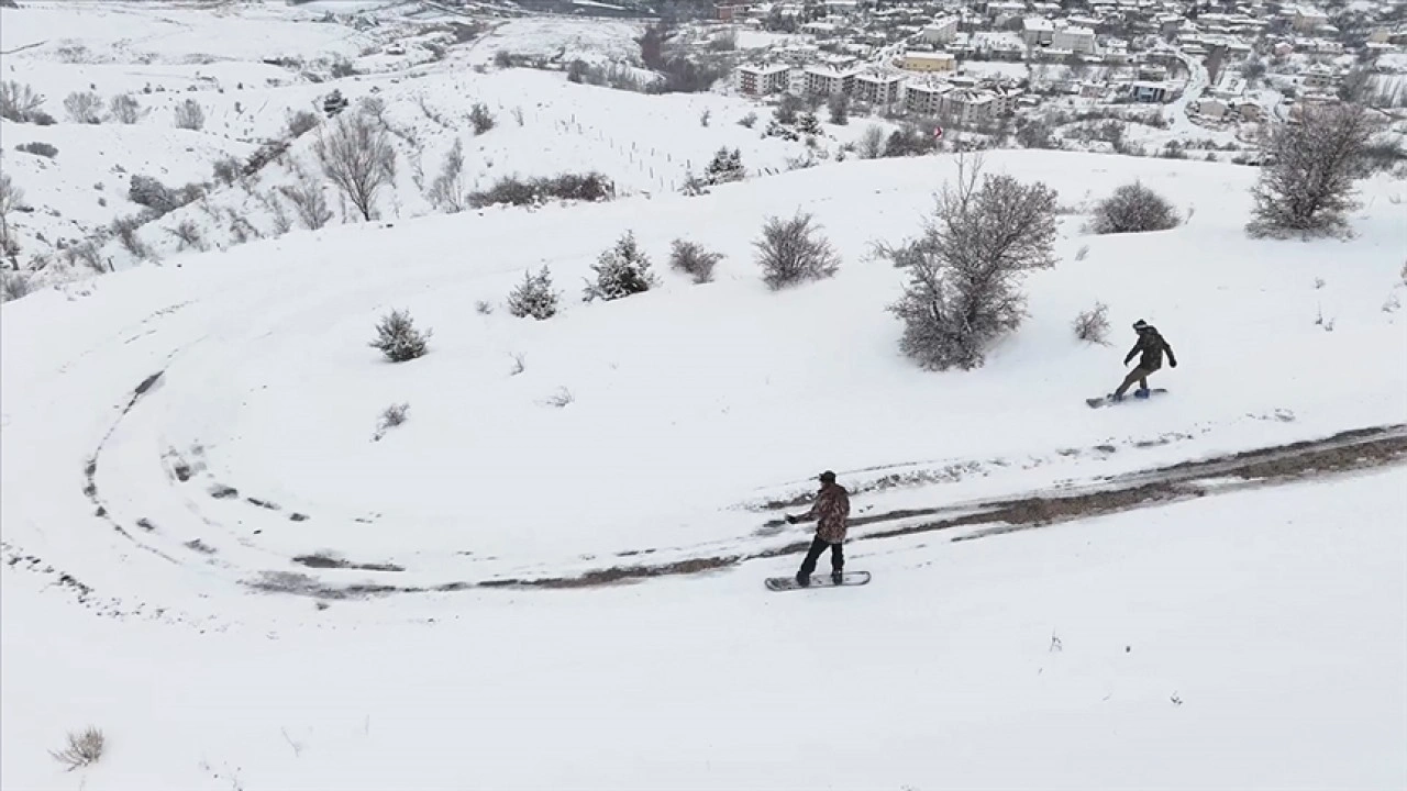 Erzincan'ın tarihi Kemah il&ccedil;esinde snowboardcular dağdan il&ccedil;e merkezine kayarak indi