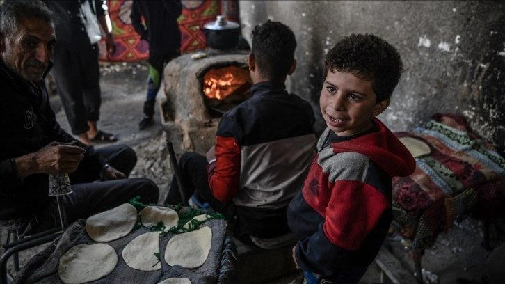 Han Yunus'taki kampta kilden yaptığı fırında yerinden edilen Filistinliler için ekmek pişiriyor
