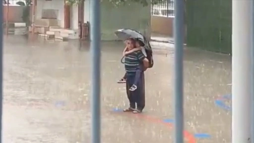 Adana'da bir kişi sağanakta sırtına aldığı torunuyla İstiklal Marşı'nı okudu