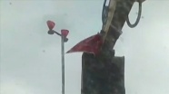 Antalya'da bir vatandaş rüzgarda kopmak üzere olan Türk bayrağını kepçeye çıkarak yerinden aldı