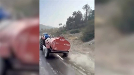 Bursa'da bir çiftçi, patlayan lastiğe rağmen yangına su taşıdı