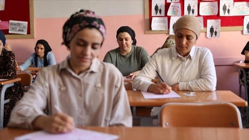 Kitap okuma yarışmasına katılan anneler çocuklarının oturduğu sıralarda sınava girdi